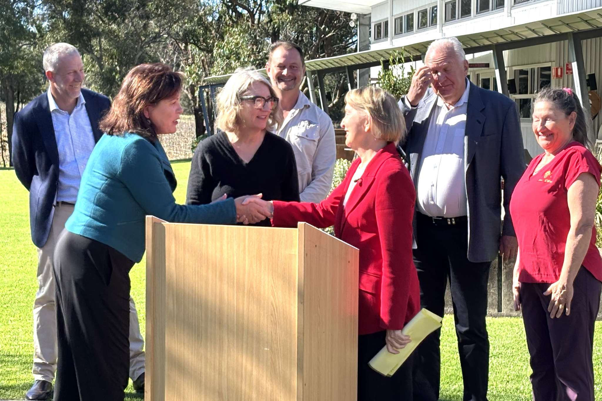 Minister for Finance, Trade, Employment and Training, Ros Bates (front right), congratulates Stanthorpe and Granite Belt Chamber of Commerce President, Michelle Feenan (front left), in the company of collaborators of 'The Precinct' including Southern Downs Regional Council Mayor Melissa Hamilton (front middle), and (from left and back) Principal of Stanthorpe State High School, Justin Kuskie, winemaker Nick Clark, representative of GBWT, Martin Feenan and winemaker Anne Bourke.